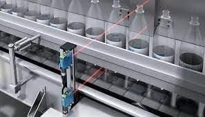 Sensor detectando nivel de llenado en línea de embotellado